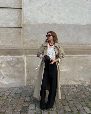 Woman wears trench coat, black trousers and shirt