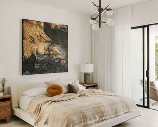Modern bedroom space in neutral tones set off by pops of color in throw pillows and one large statement piece of artwork above the headboard