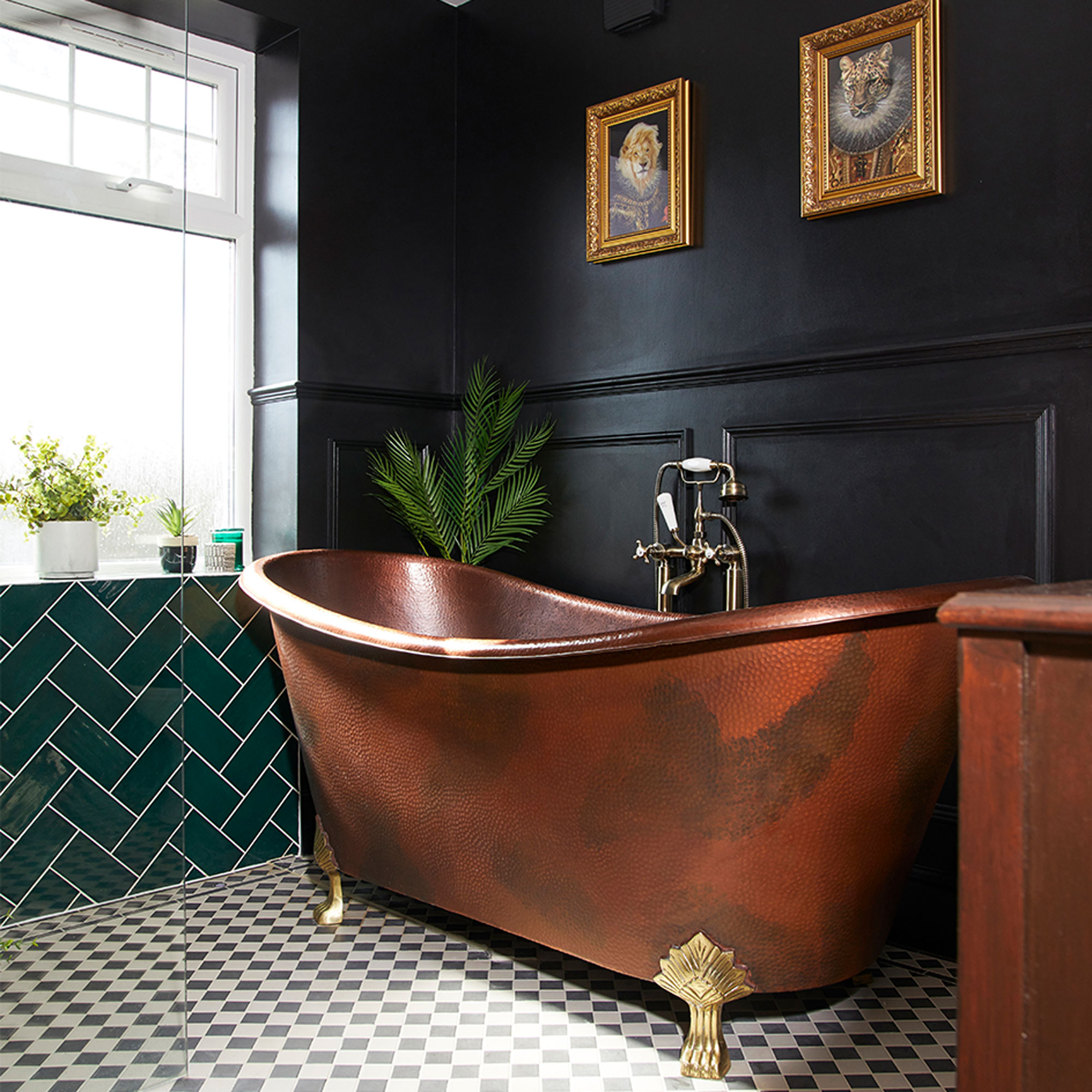 Black bathroom with copper bath and monochrome floor tiles