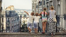 A family of four looks out at the Paris city skyline.