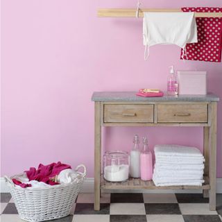 pink utility room with wooden table and basket