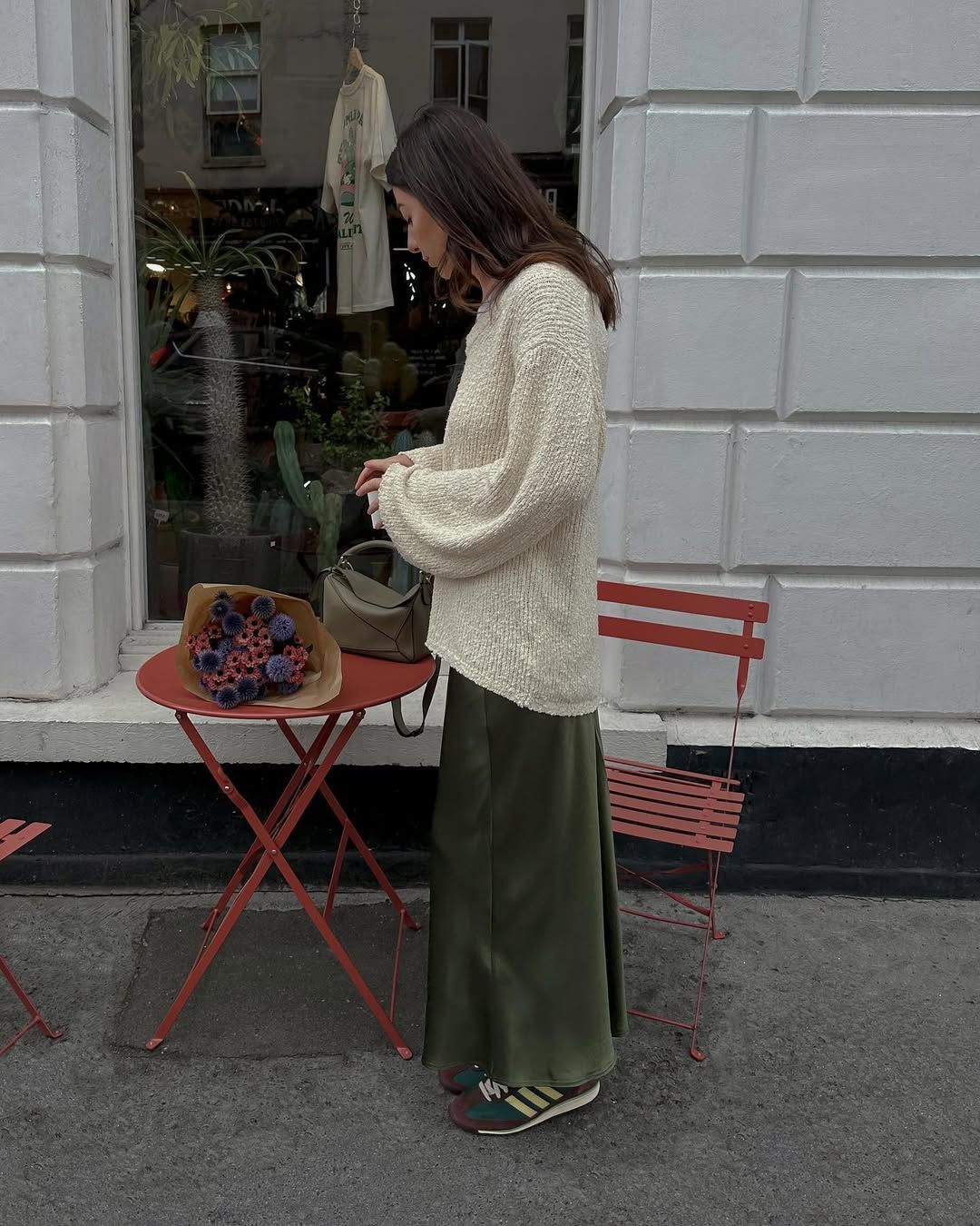 @francescasaffari wears a khaki satin skirt with green trainers and a cream jumper