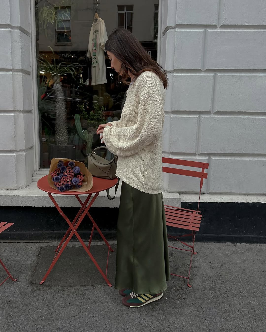@francescasaffari wears a khaki satin skirt with green trainers and a cream jumper