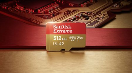 A close-up of a 512GB SanDisk Extreme microSD card on a gold and red circuit board backdrop, highlighting its speed and performance features.