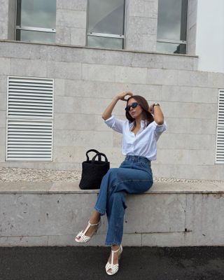 influencer mode @deborabrosa mengenakan kemeja berkancing, celana jins biru, dan sepatu hak T-strap