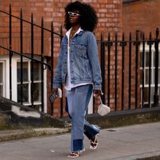 London spring fashion week attendee wearing a jean jacket and jeans and white button down shirt 