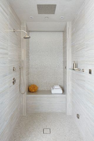 walk shower with neutral tiles, mosaics, shower bench, chrome shower