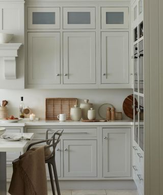 A white kitchen with styled coutnertops, chopping boards and baskets line the wall, with a woven wicker basket