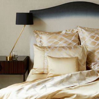 bedroom with golden linen pillows and black table lamp