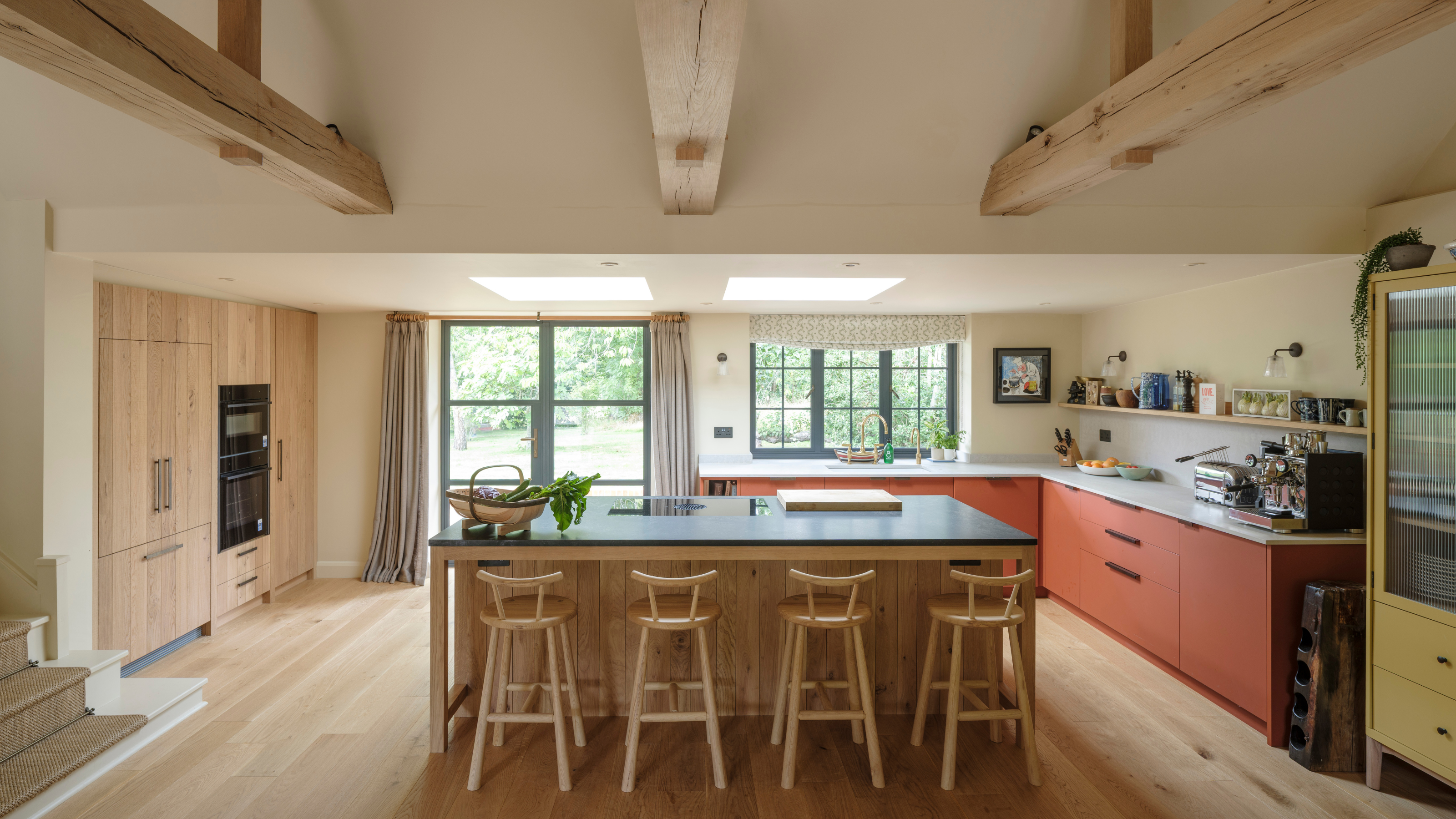 beautiful, big kitchen with wooden beams across the ceiling, sawn wood cabinetry and some rust colored cupboards