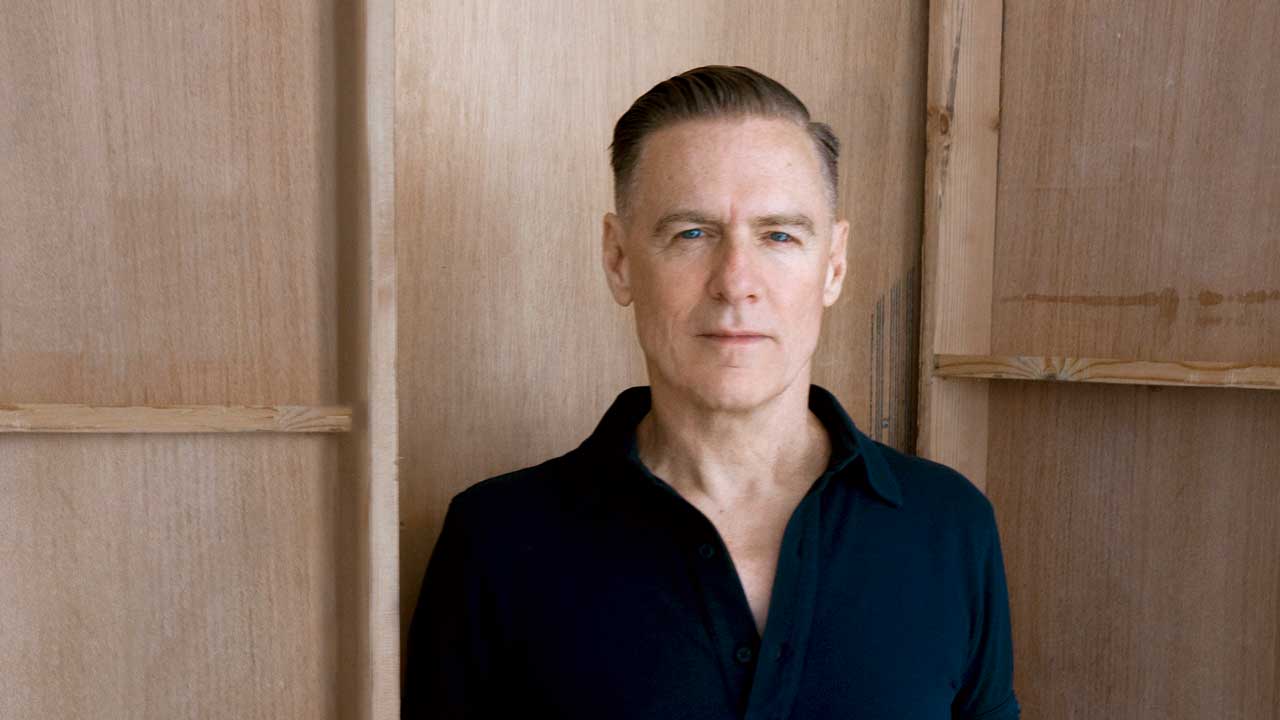 Bryan Adams pictured against a wooden background
