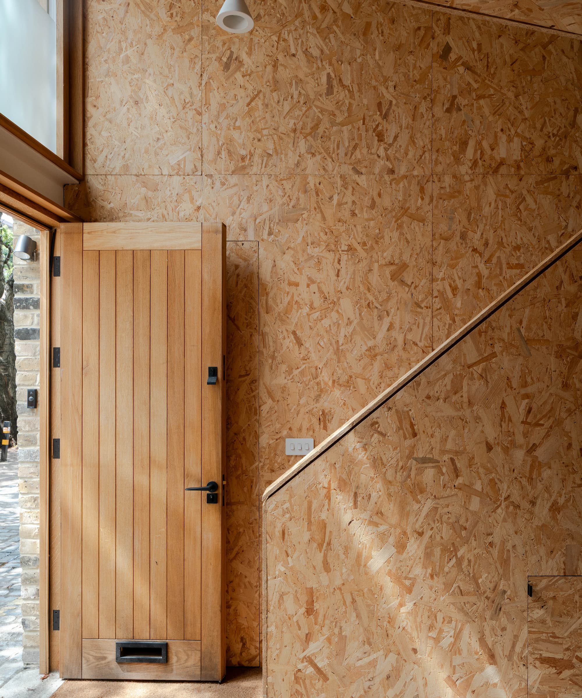 A plywood staircase in front of a wooden front door