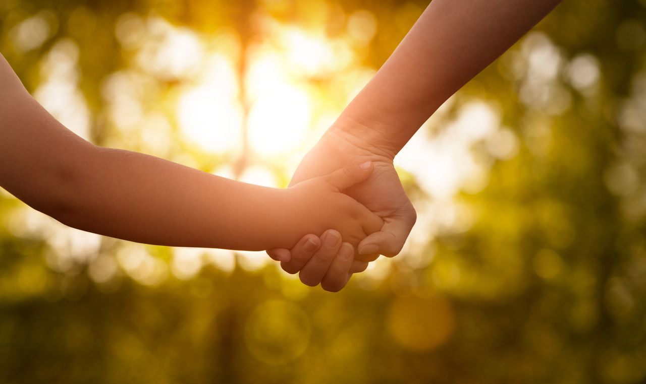 A parent holds hands with their child.