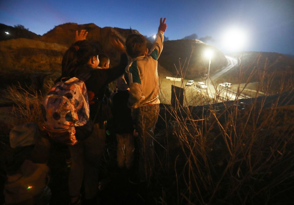 Central American migrants wave at U.S. Border Patrol agents