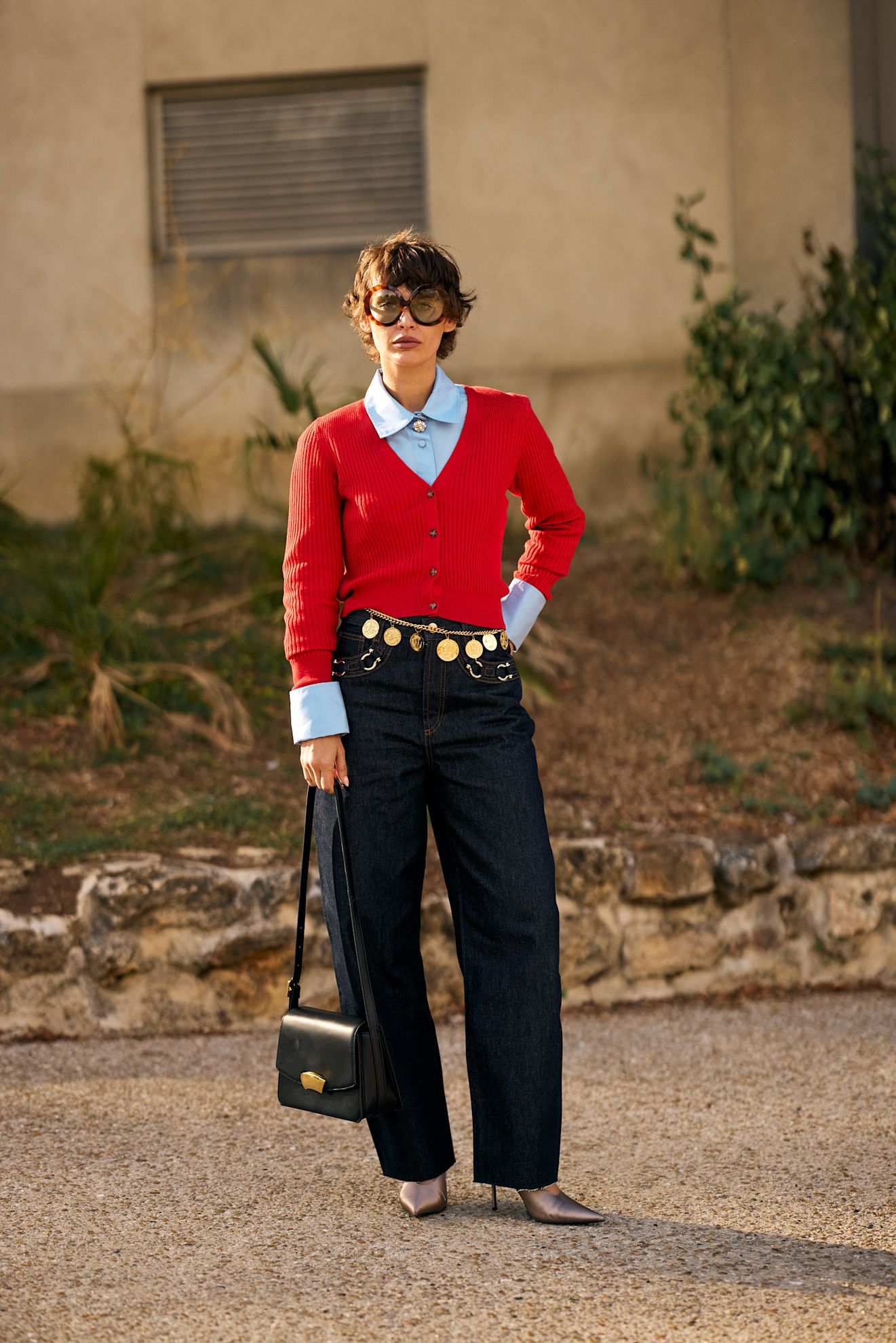 Paris Fashion Week attendee wears blue jeans with a blue shirt and red top.