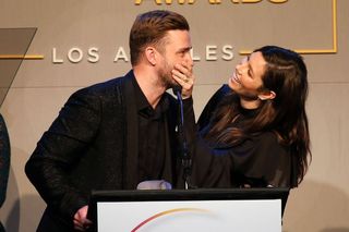 Jessica Biel and Justin Timberlake dressed in black laughing at podium with mic