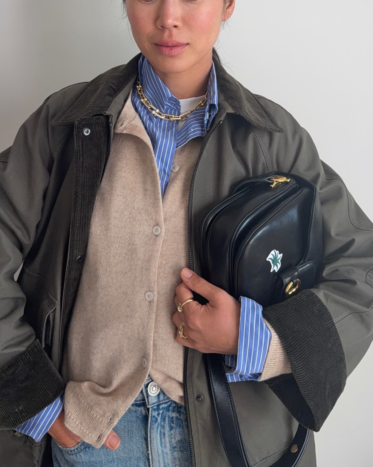 Woman in jeans, a button-down, cardigan, and barn jacket.