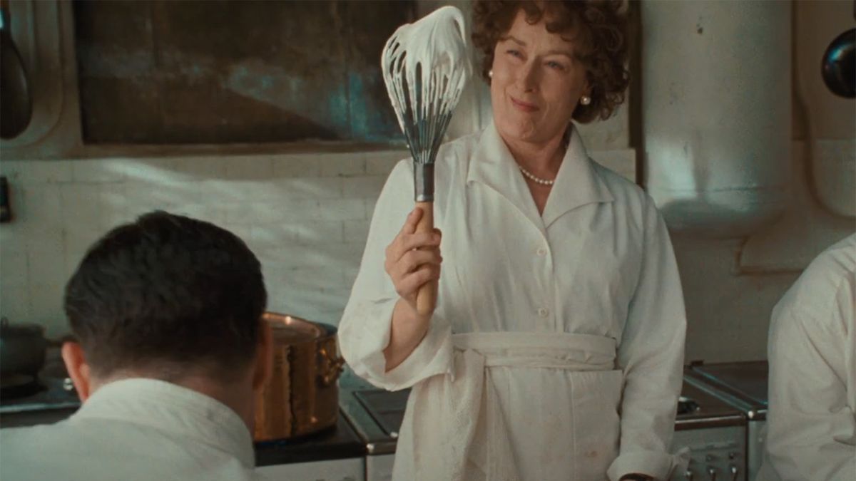 Meryl Streep cooking in the kitchen and holding a whisk in Julie &amp; Julia. 