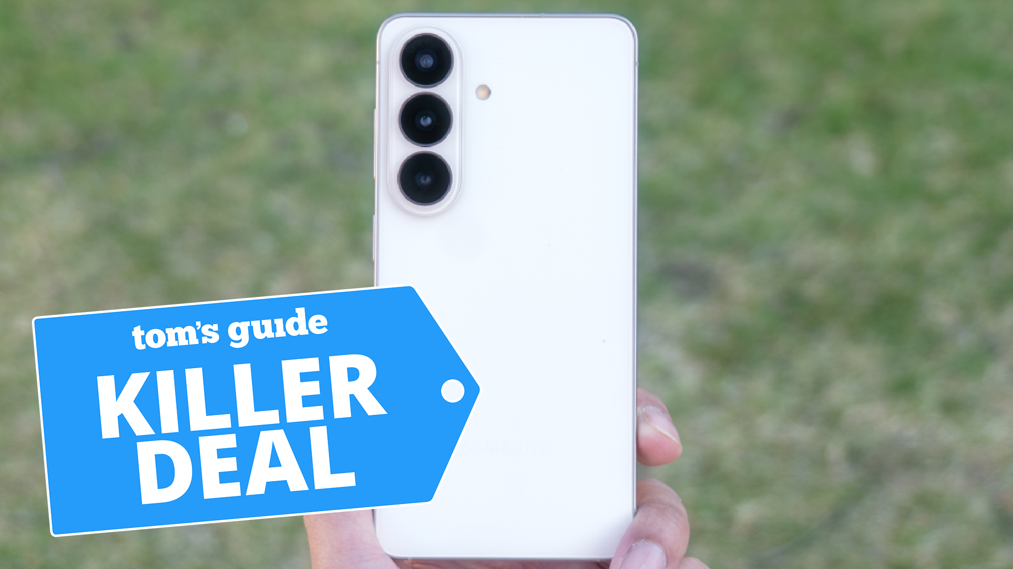 Galaxy S26 held in hand in front of grass