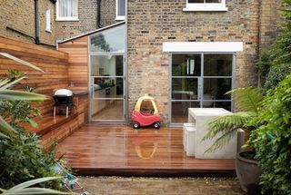 a three storey Victorian terraced house side return extension, with a wooden deck outside and a toy car