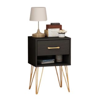 A black nightstand with gold legs and a lamp on top of it