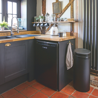 Black bin placed next to black kitchen cupboards.