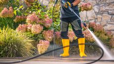 Pressure washing a patio in front of flowers