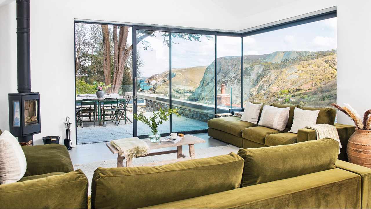 Green sofa in living room with floor to ceiling windows