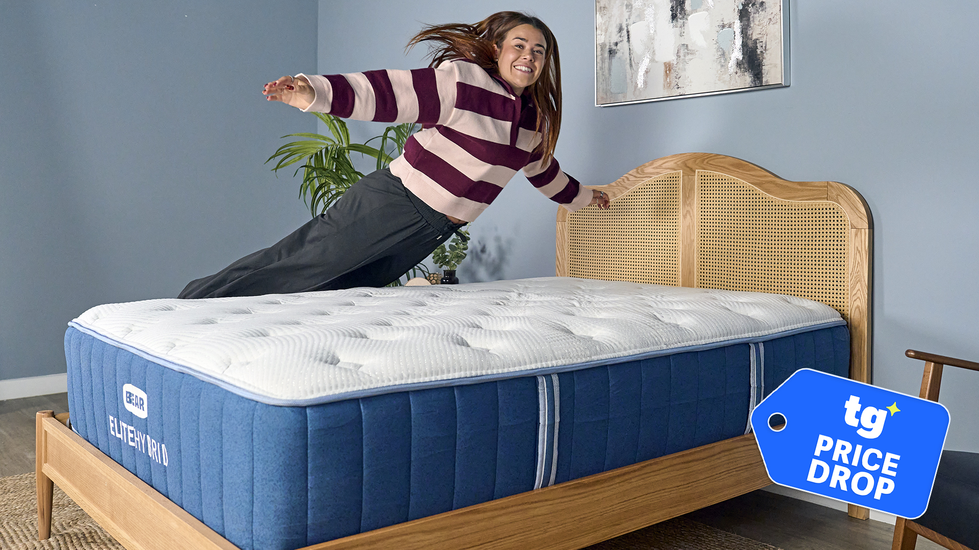 Mattress tester Eve Davies leaps on to the Bear Elite Hybrid mattress in our sleep studio. In the bottom left corner is a Tom's Guide price drop deals graphic