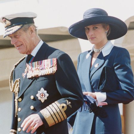 Prince Philip wears military uniform and Princess Diana wears a navy coat dress with a large-brim hat