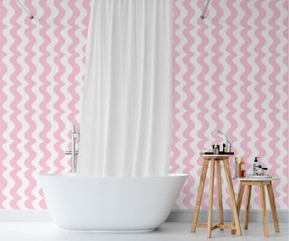 pink and white wavy wallpaper behind white freestanding bath and white shower curtain