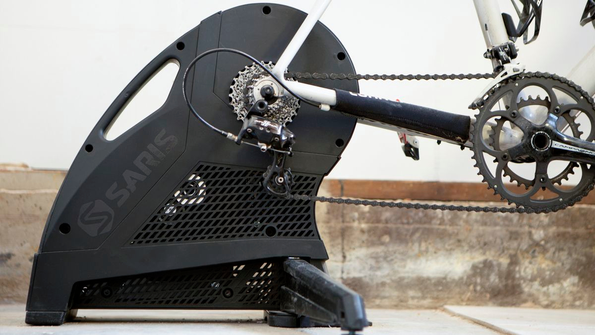 Side angle of the Saris H3 Plus Smart Trainer outside in front of a wall