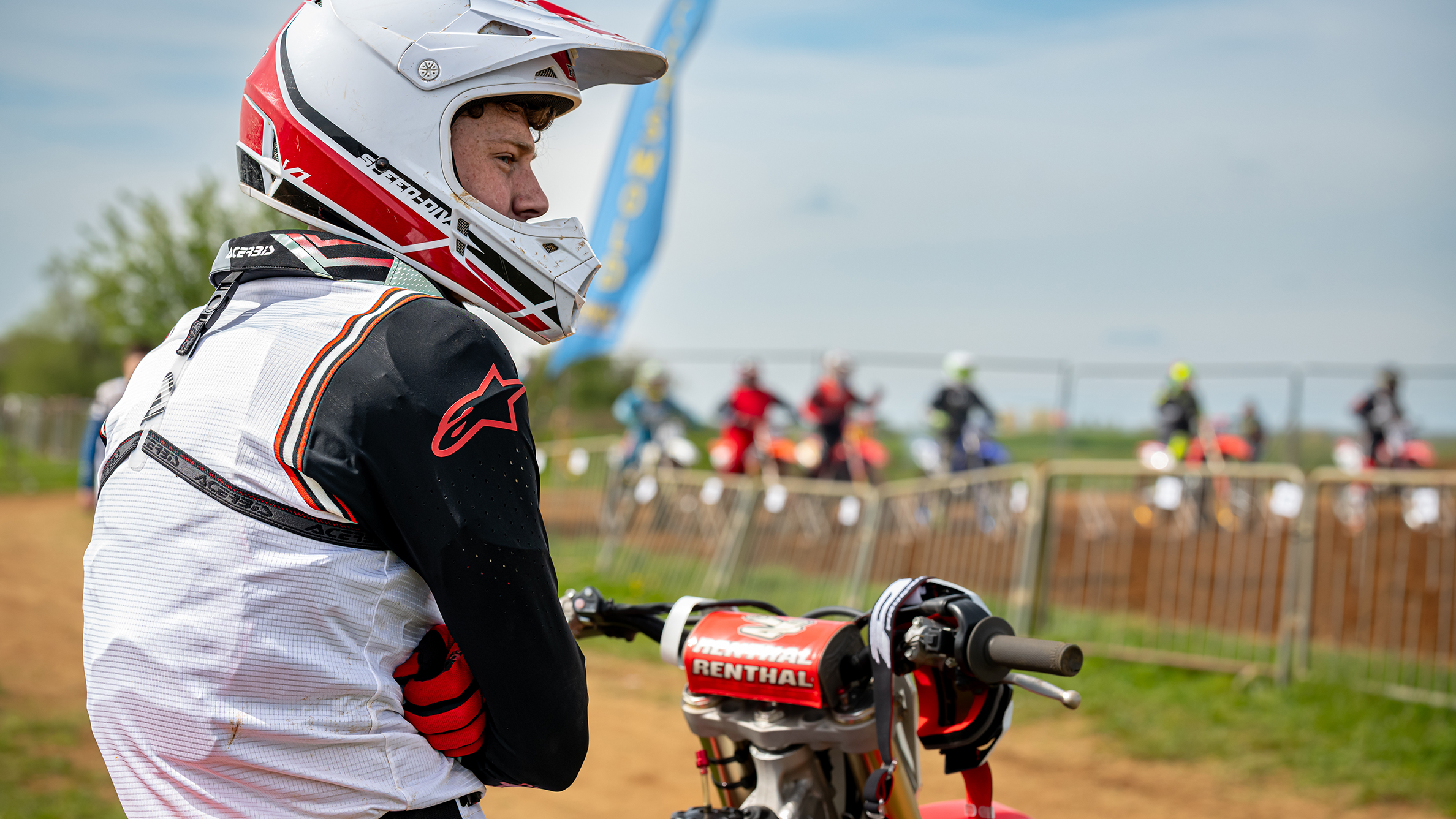 A motocross rider sitting on his bike, shot from the side