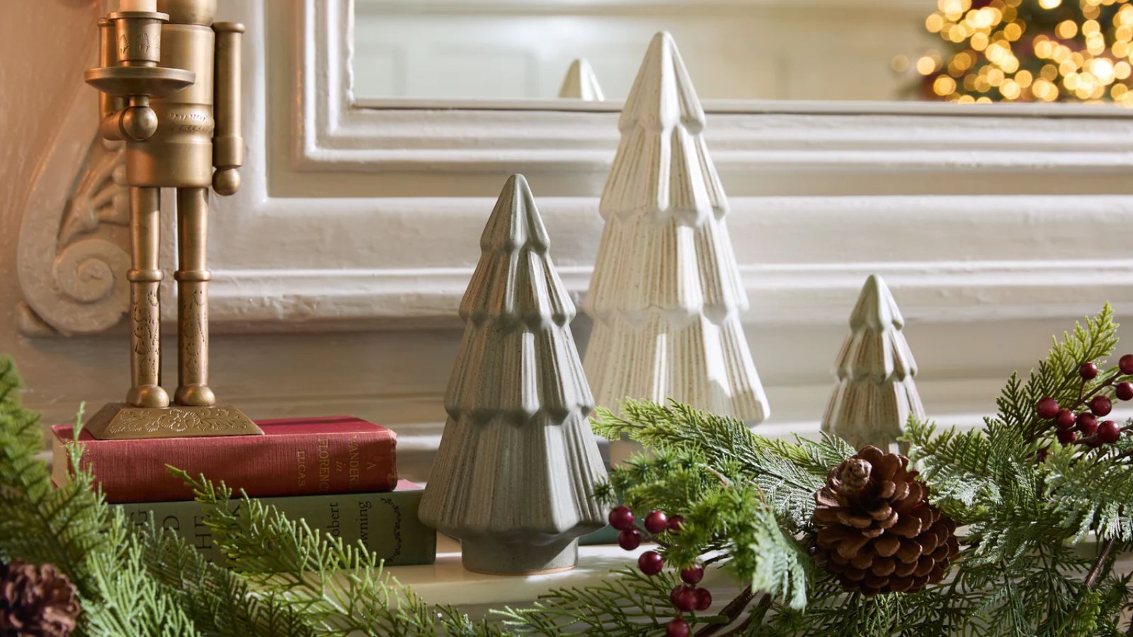 Close up of fireplace mantel with christmas foliage, small christmas tree ornaments and books