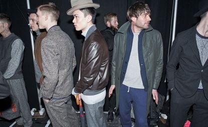 A group of men waiting around for a fashion show