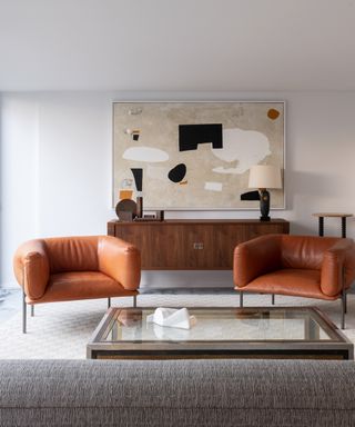warm vs cool colors, modern living room with retro sideboard and tan leather armchairs, modern artwork, large glass topped coffee table, white walls