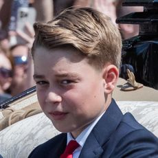 Prince George at Trooping the Colour 2025 wearing a navy suit with a white shirt and a red tie, and joining the Royal Family on the Buckingham Palace balcony