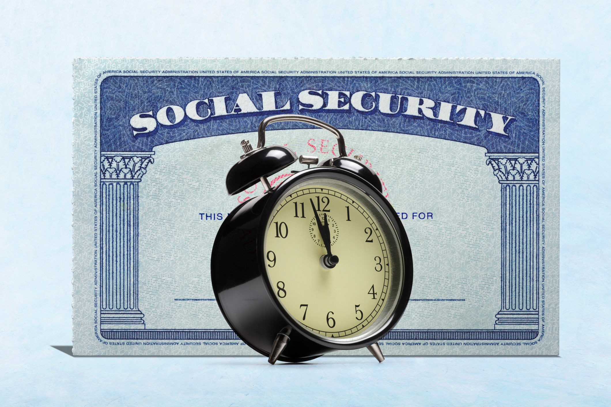 An alarm clock stands in front of a Social Security card.