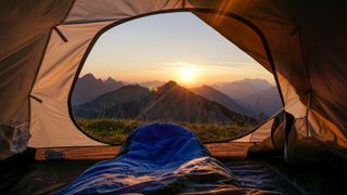 Mountain view from entrance to a tent, showing sleeping bag in foreground