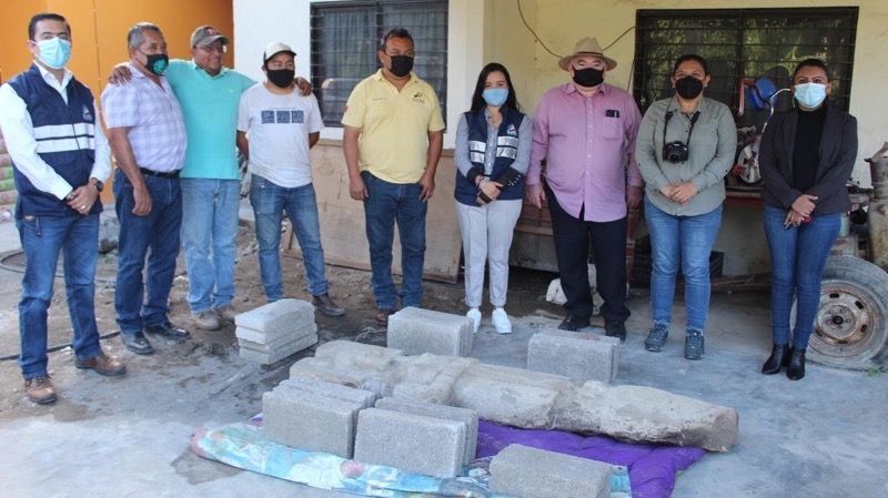 The excavation team stands next to the statue.