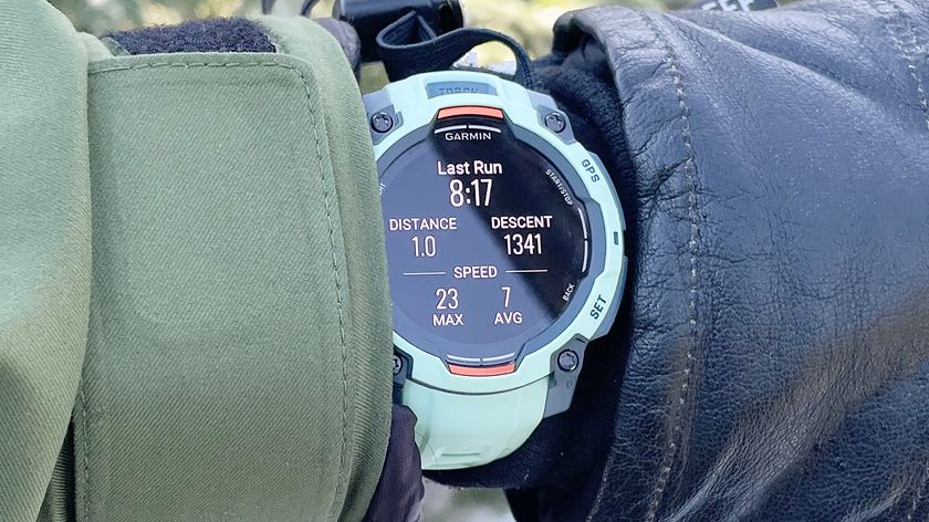 Garmin Instinct 3 on a user&#039;s wrist shown up-close in between a ski glove and jacket