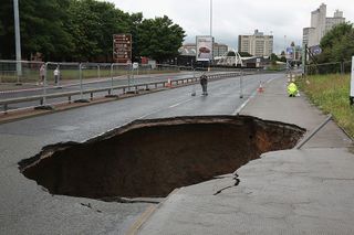 A sinkhole appears on Mancunian Way in Manchester after heavy rain on August 14, 2015 in Manchester, England.