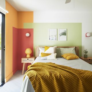 bedroom paint ideas, trio of colour blocks, green, red and orange, yellow throw, artwork, bedside, lamp