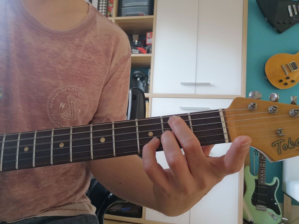A person playing the open B minor 7 (Bm7) on electric guitar