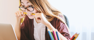 Employee on her laptop frustrated, biting pencil 