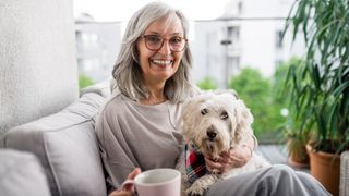 Easy ways to teach your dog new tricks — woman sitting on sofa with a cup of tea and her dog