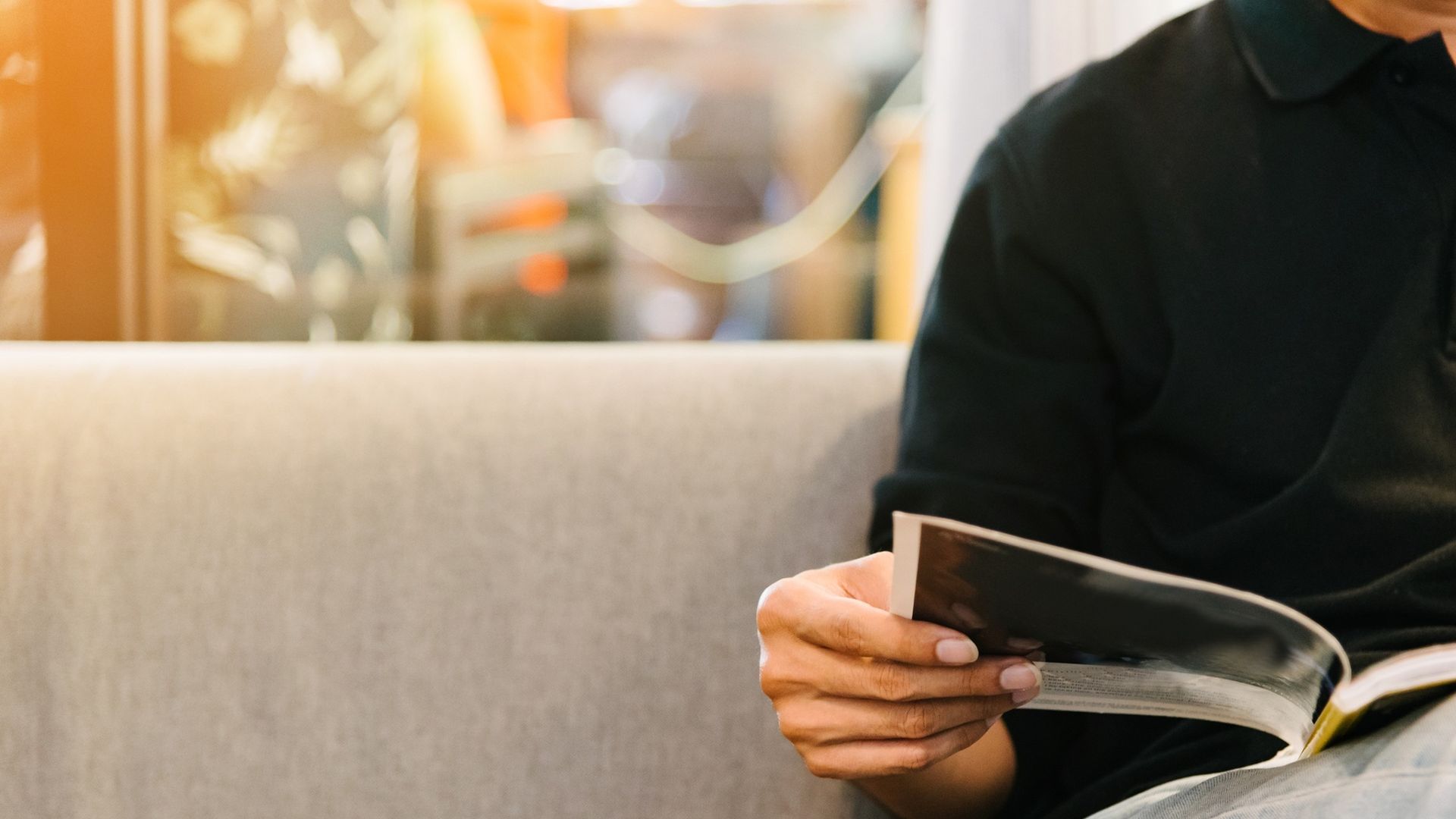A man reading a magazine on a sofa.