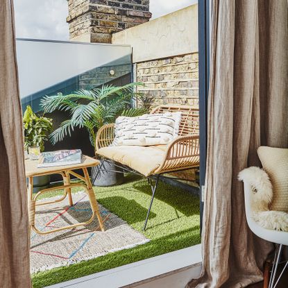 Small balcony with artificial grass and rattan furniture