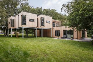 A raised timber frame home with timber clad walls and a lower floor, open plan leading onto the garden