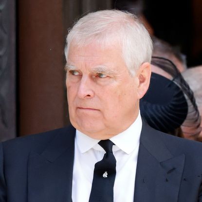 Prince Andrew wearing a dark suit and scowling